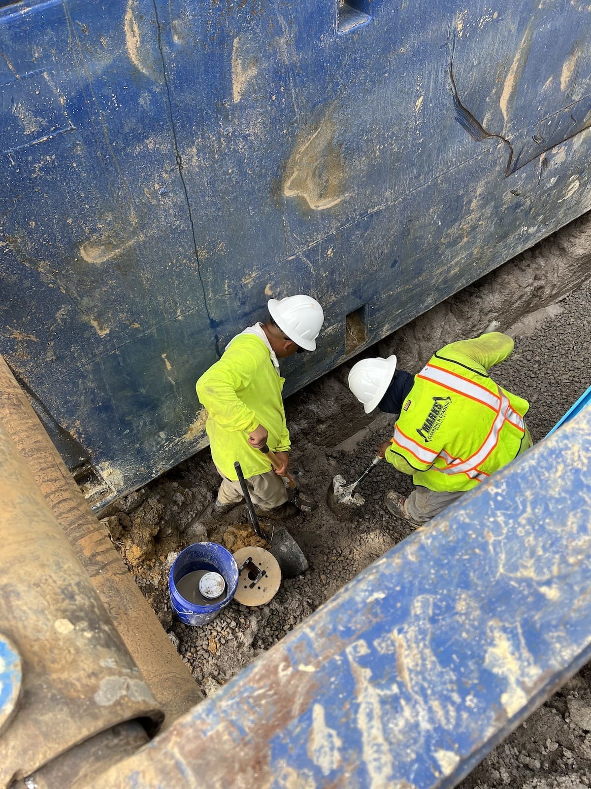 Marks crew member connecting underground utility pipe