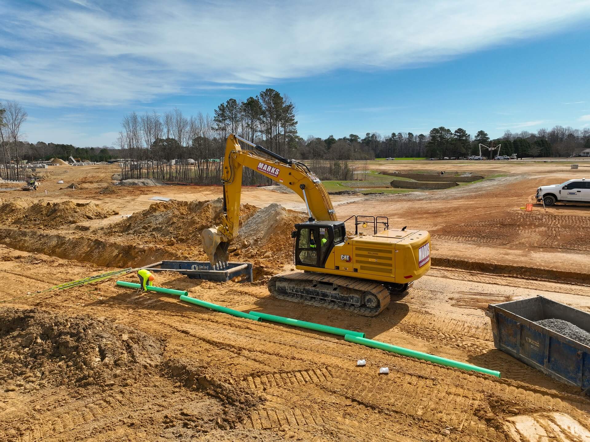 Marks excavator installing pipe with a trench box on a Triangle development