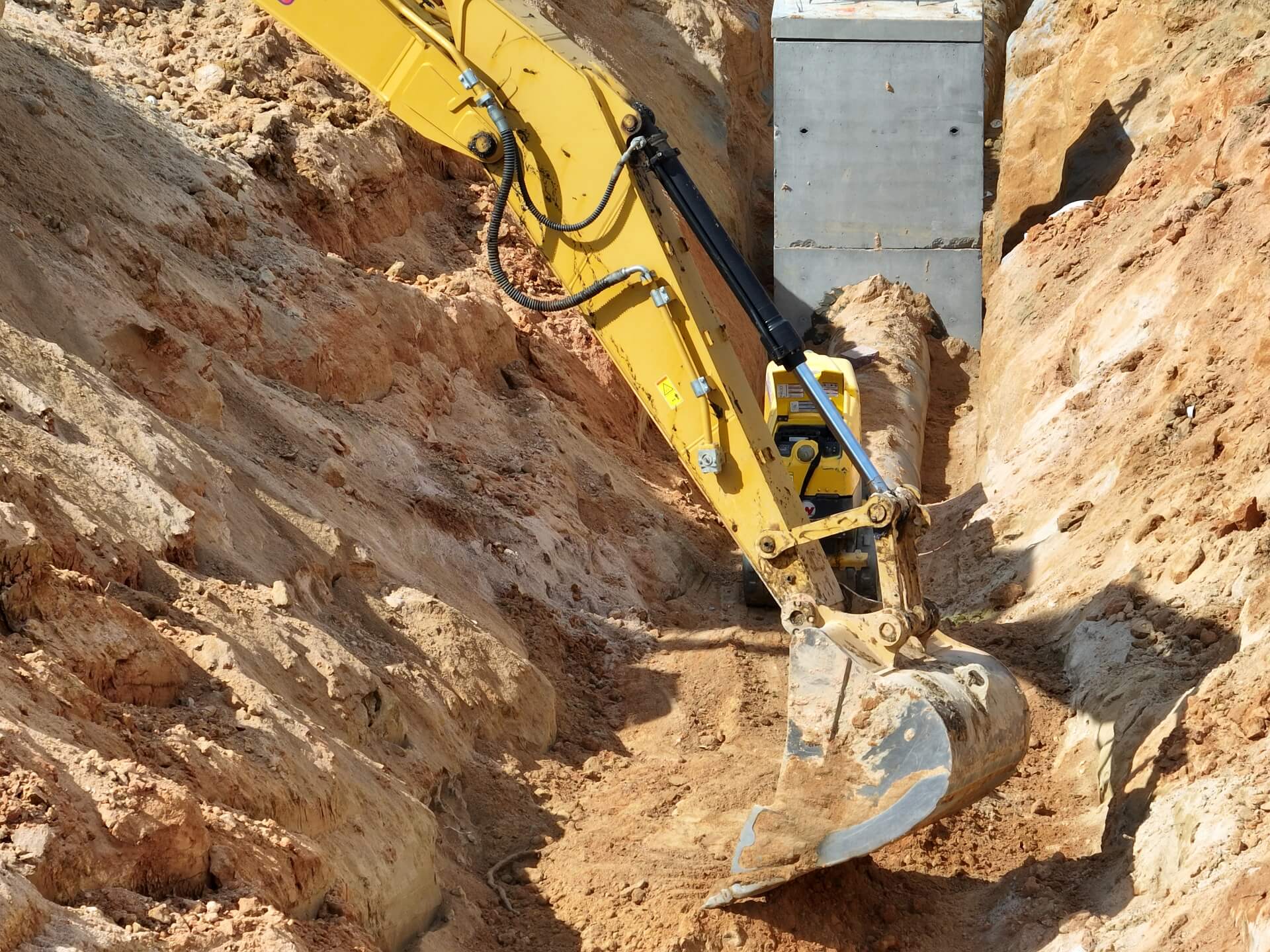 Excavator bucket working alongside a precast utility structure