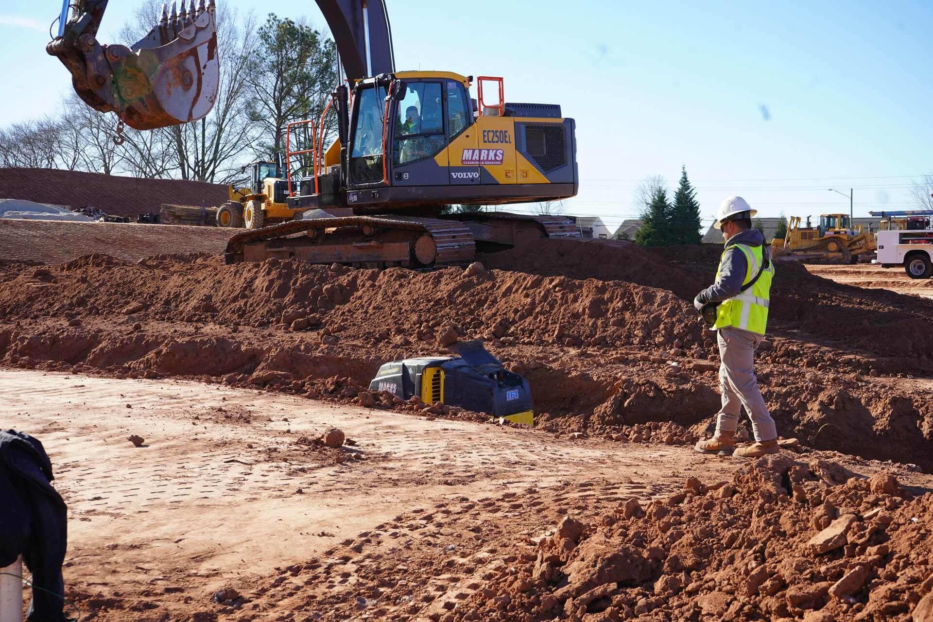 Marks excavator and spotter setting pipe grade