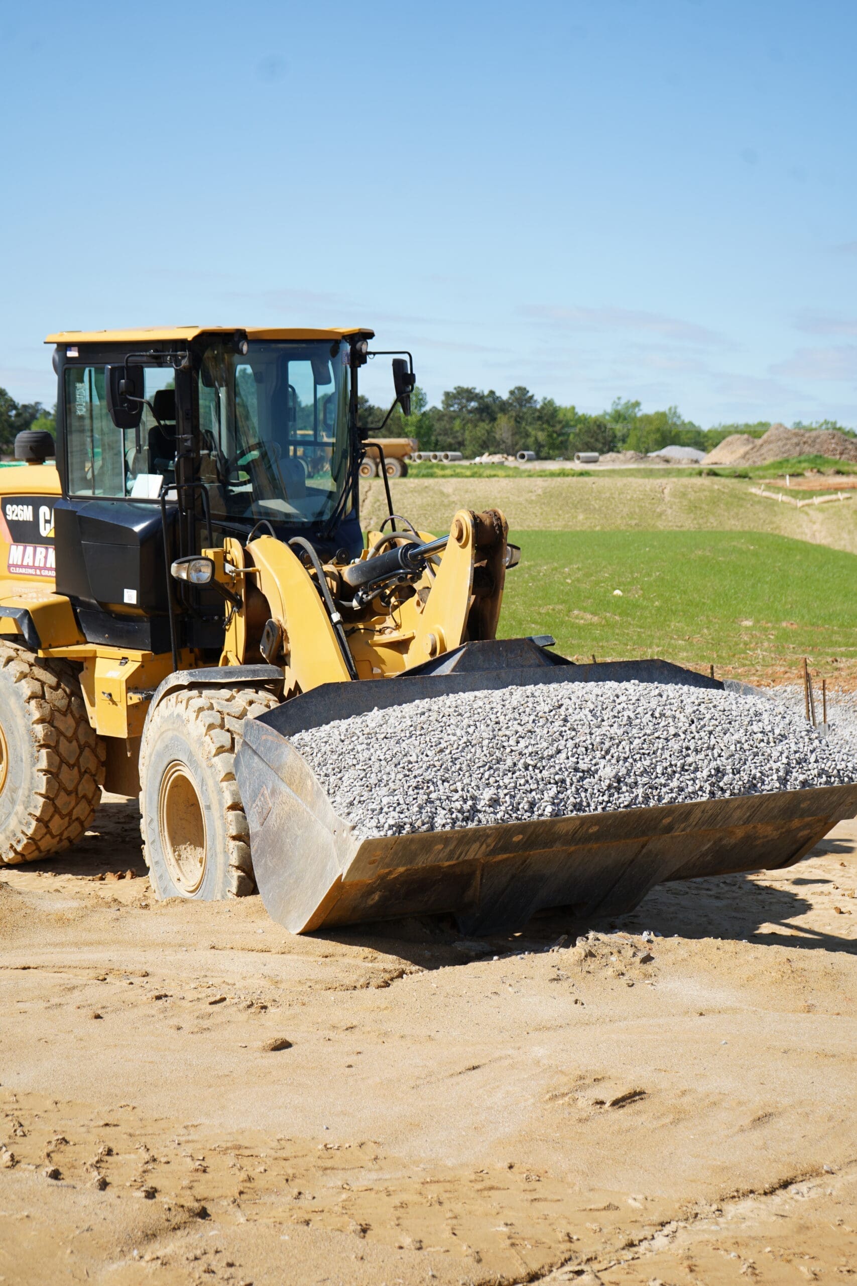 Cargadora de la marca Marks colocando piedra de base en una carretera