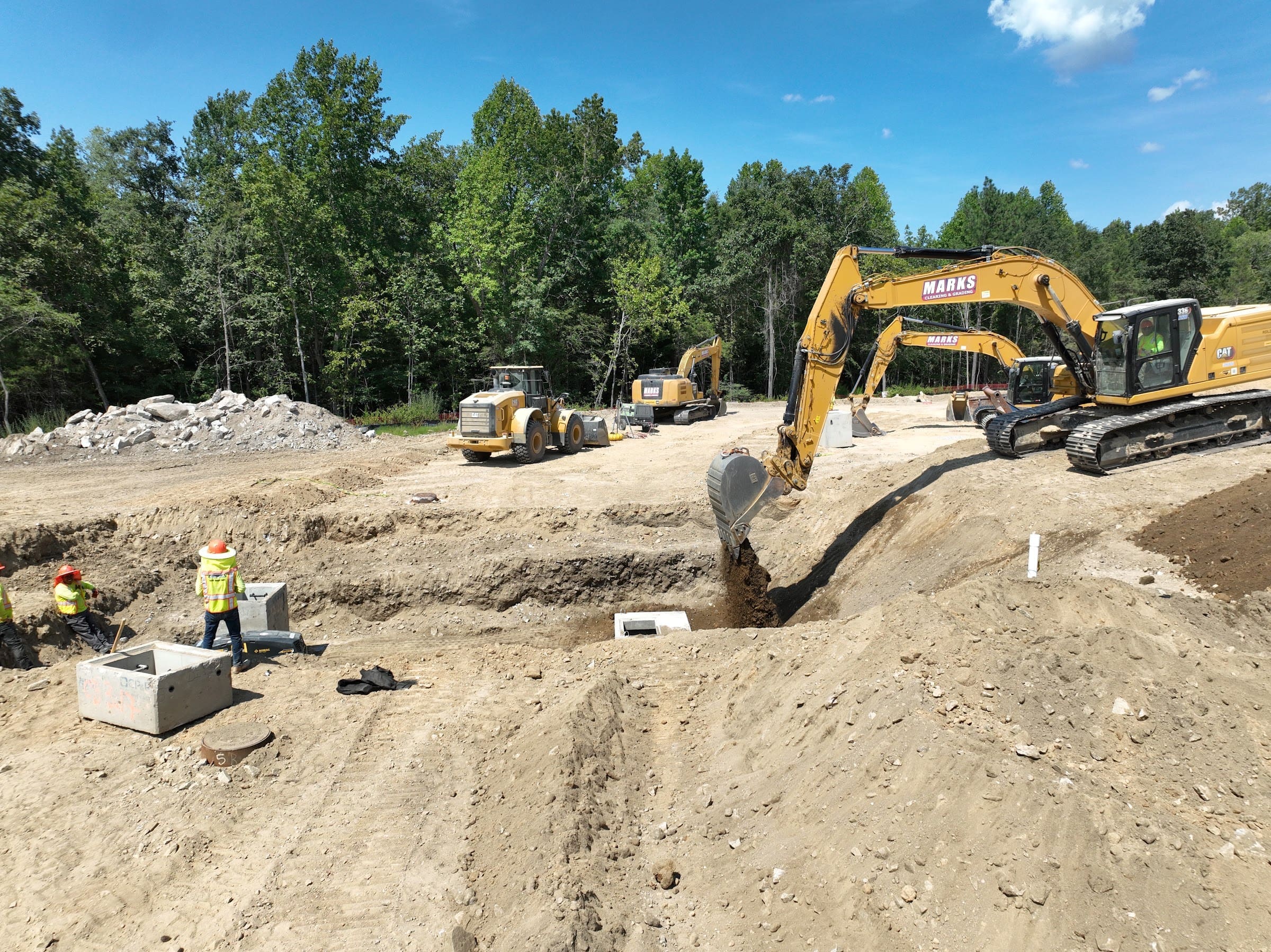 Marks utility crew and excavators working a site excavation